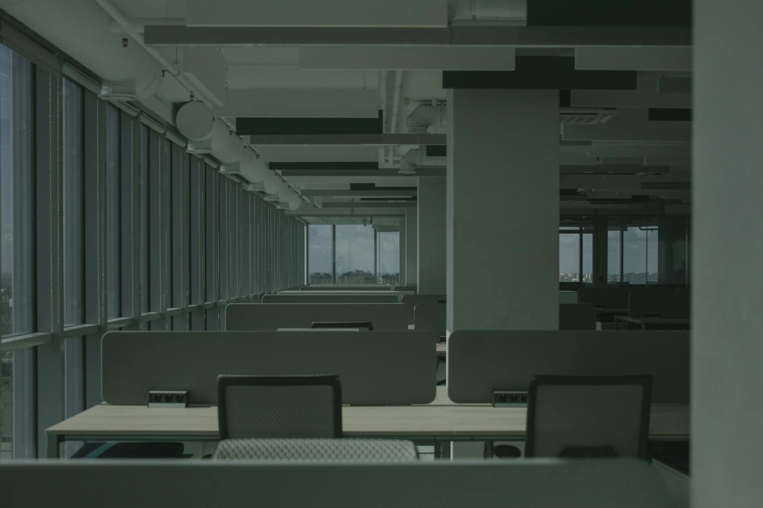 Why Corporate Flexible Work Policies Are Reducing Commercial Insurance Costs Modern empty office space with desks and chairs showing reduced occupancy