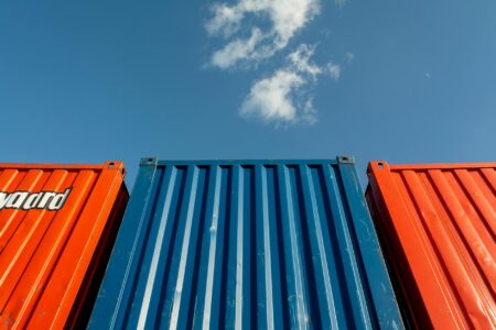 How Trade War Tariffs Are Affecting Small Business Import Strategies Colorful shipping containers stacked at international trade port representing global supply chains