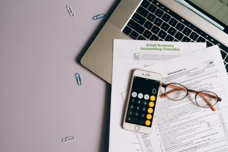 Why gig Economy Tax Changes Are Reshaping Independent Contractor Benefits Person working on laptop with calculator and tax documents on desk
