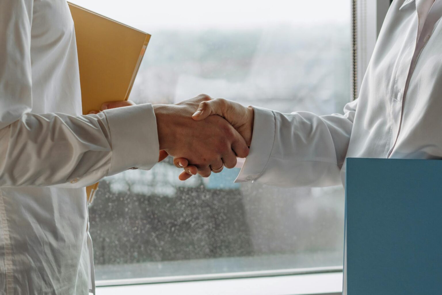 How Corporate Climate Pledges Are Reshaping Supplier Contract Terms Business professionals shaking hands over contract documents