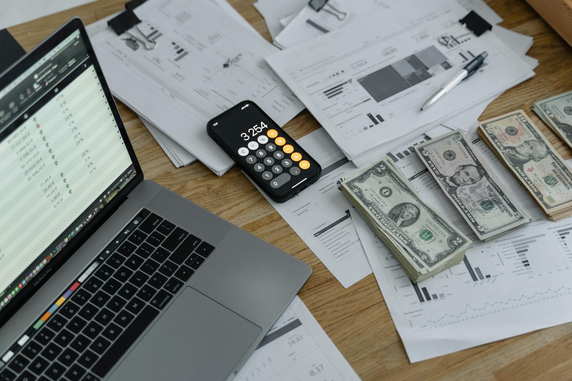 Financial planning workspace with calculator, laptop, and money representing content monetization
