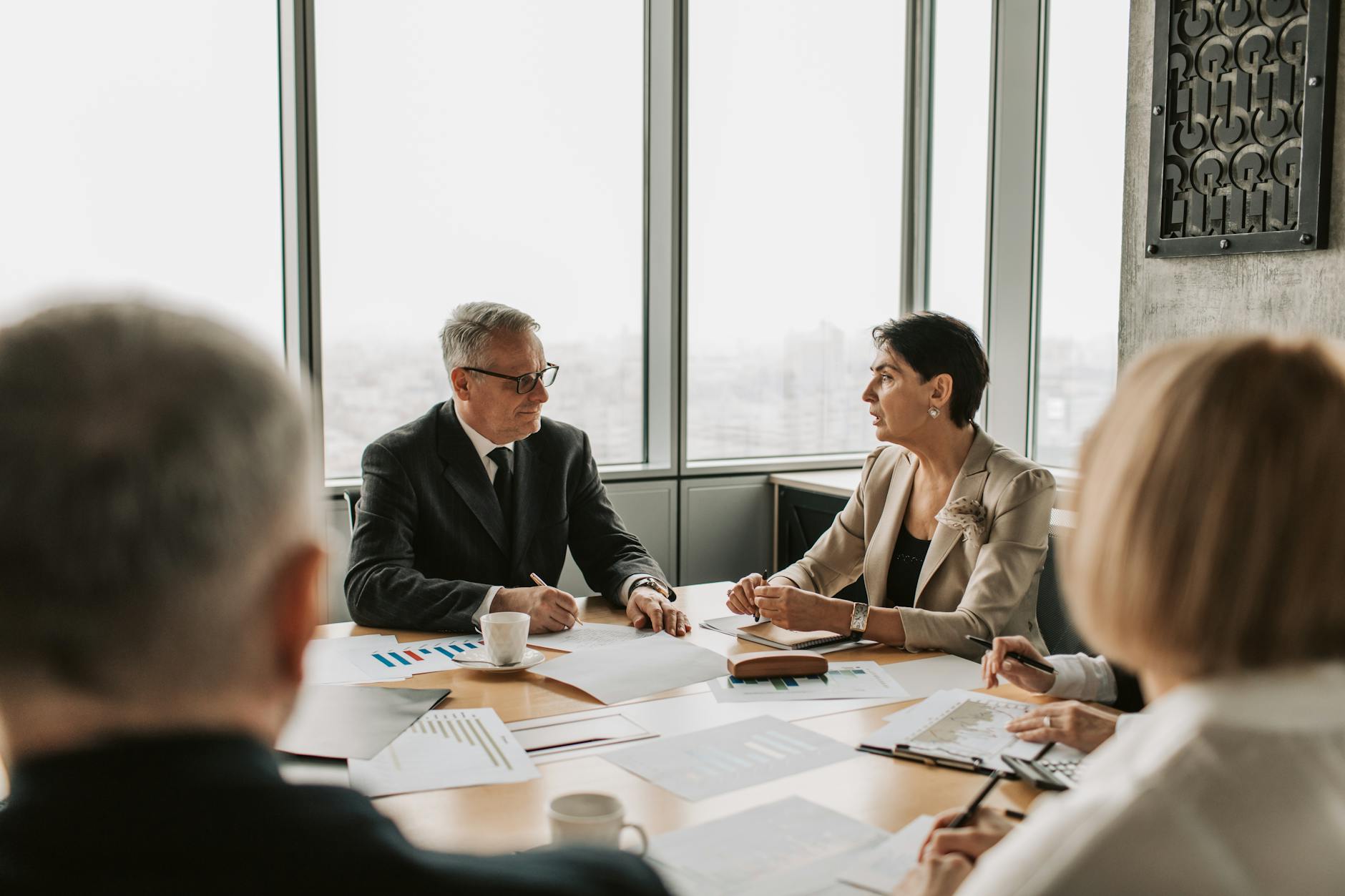 Business executives reviewing financial documents in a corporate boardroom setting