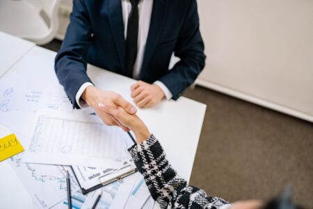 Two professionals shaking hands over a financial transaction, representing a secondary market deal