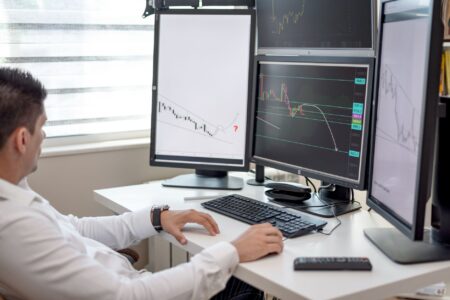 Traders monitoring live financial data on multiple screens in a busy trading floor environment