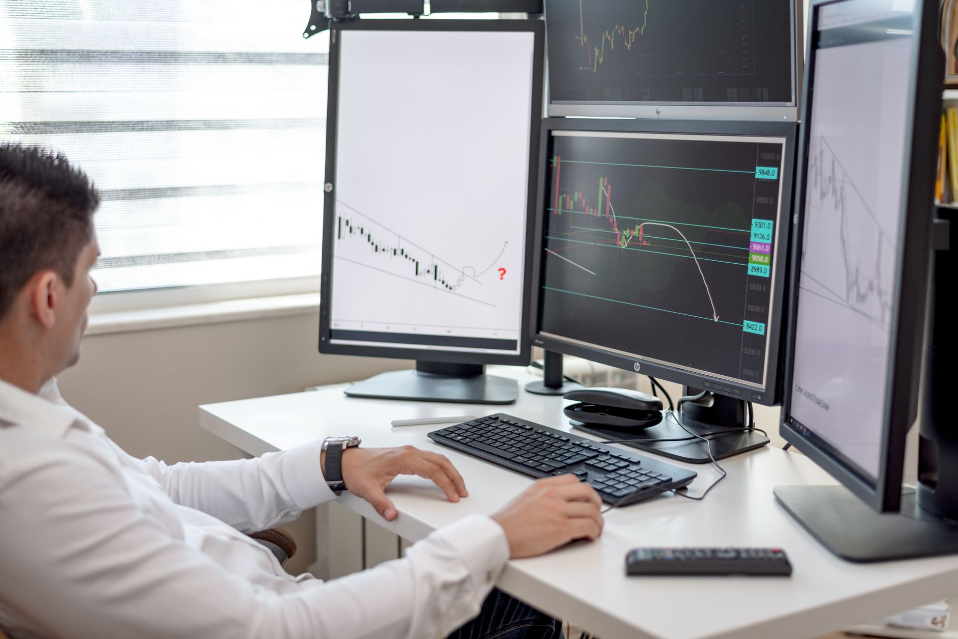 Traders monitoring live financial data on multiple screens in a busy trading floor environment