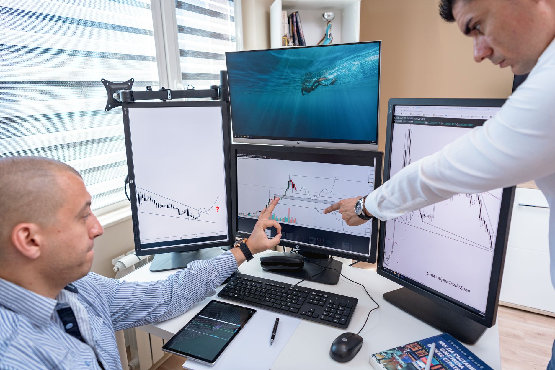 Trader working at desk surrounded by multiple financial data monitors