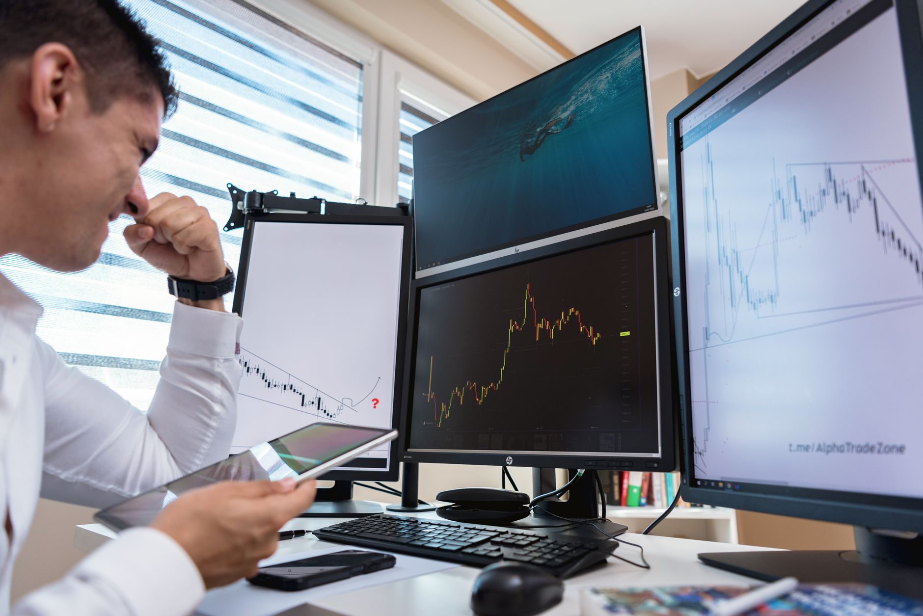 Trader monitoring multiple financial data screens in a professional trading environment