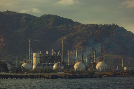 Industrial oil refinery with pipelines, representing energy price dynamics and inflation risk